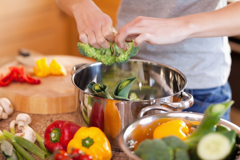 Op de afbeelding is een kok bezig met groenten een maaltijd te bereiden