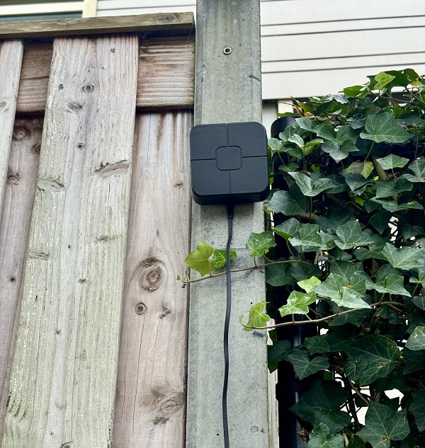 Afbeelding van meetapparatuur bevestigd aan een schutting in een tuin.