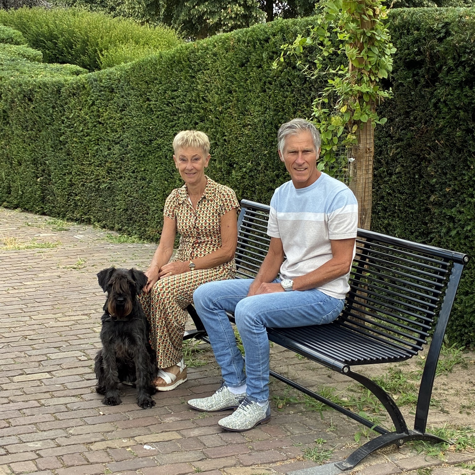 Foto met een vrouw, man en een hondje op een bank zittend